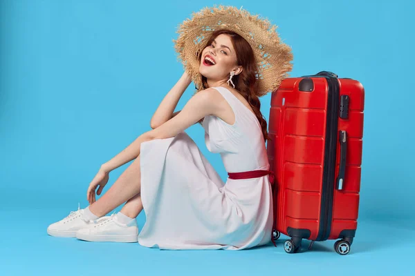 Veselá žena v klobouku sedí na podlaze s kufříkem cestovní destinace — Stock fotografie