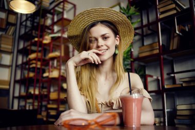 Kafe modasında kitap okuyan neşeli bir kadın.