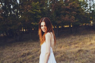 Beyaz elbiseli güzel bir kadın doğada özgürce yürüyor.