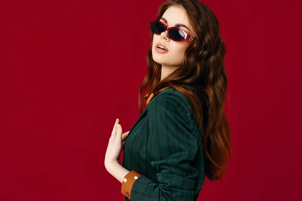 Kvinna i kostym solglasögon poserar glamour röd bakgrund — Stockfoto