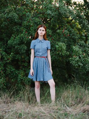 Kırmızı saçlı güzel kadın yeşil çalı gibi poz veriyor.