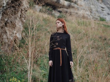 Siyah elbiseli kadın dağlarda özgürce dolaşıyor.