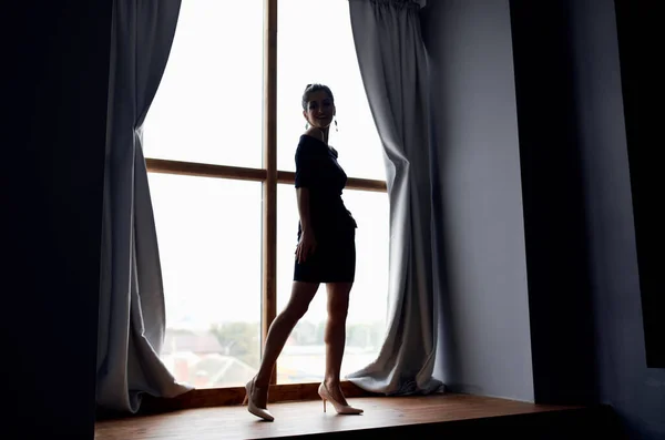 站在窗前，穿着黑色衣服，摆姿势的女人 — 图库照片