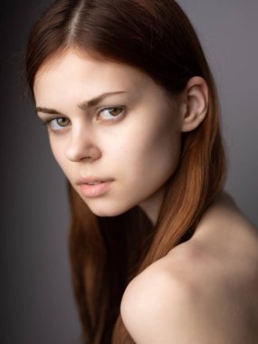 Güzel bir kadın, kızıl saçlı, çıplak omuzlu. Yaşam Tarzı Stüdyosu pozu veriyor.