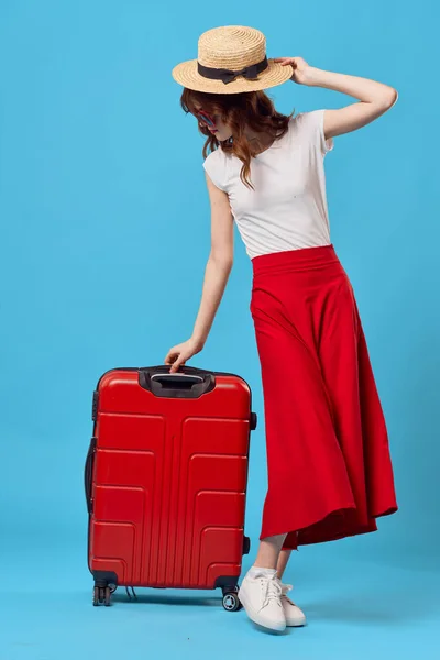 Femme assise sur une valise rouge voyage style de vie vol fond bleu — Photo