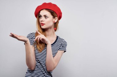 Çizgili tişörtlü güzel bir kadın. Kırmızı dudaklı, elleri açık arka planlı.