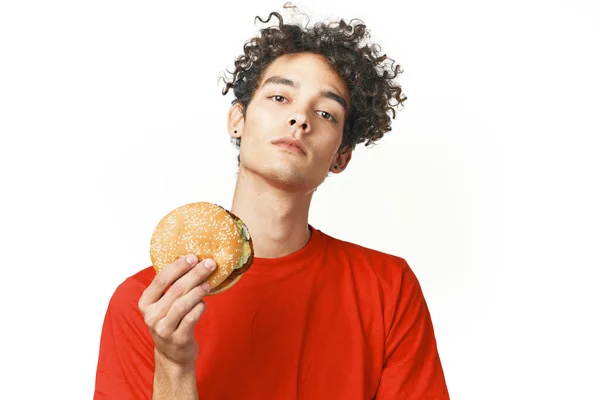 Σγουρομάλλης τύπος fast food στα χέρια ενός σνακ τροφίμων δίαιτα φως φόντο — Φωτογραφία Αρχείου