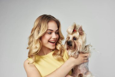 Sarı elbiseli sarışın. Eğlenceli. Küçük bir köpek izole edilmiş.