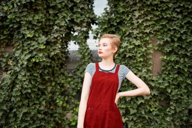 Arka planda çalıların üzerinde kısa saçlı güzel bir kadın