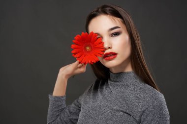 Esmer, kırmızı çiçekli, parlak makyajlı, esmer bir kadın.