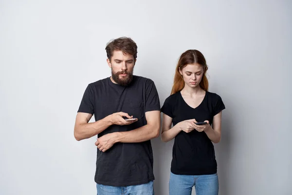 Fröhliches junges Paar mit einem Handy in der Hand Emotionen leichter Hintergrund — Stockfoto