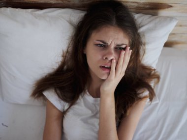 Hasta kadın yatakta elleri üzerinde uzanıyor.