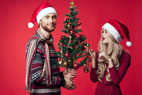 Fröhliches junges Paar mit Nikolausmützen Weihnachtsbaumschmuck — Stockfoto