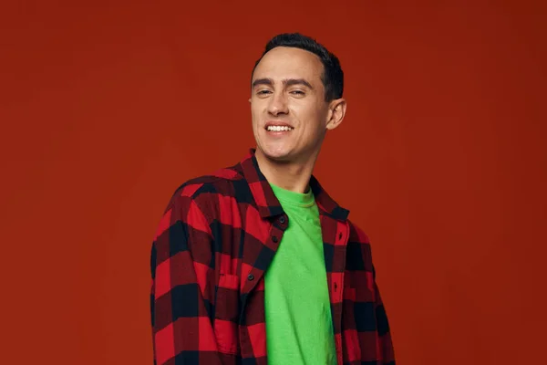 Man in een unbuttoned shirt en in een groen t-shirt op een rode achtergrond glimlach model — Stockfoto