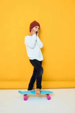 Beyaz süveterli kaykaylı havalı bir çocuk. Çocukluk hayatı konsepti.