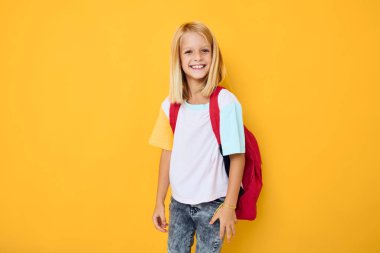 Mutlu liseli kızlar ellerini sarı arka plana koyarlar.