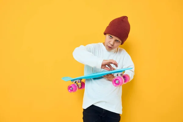 Veselý malý kluk v červeném klobouku skateboard v jeho rukou studio pózovat — Stock fotografie