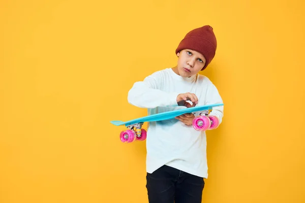 陽気な小さな子供カジュアルな青スケートボード黄色の背景 — ストック写真