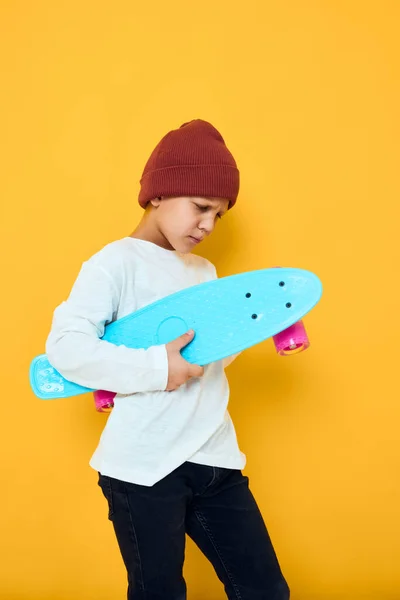 Rolig liten pojke i en röd hatt skateboard i händerna studio poserar — Stockfoto