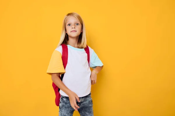 Porträtt av söta flickor med en röd ryggsäck gul färg bakgrund — Stockfoto