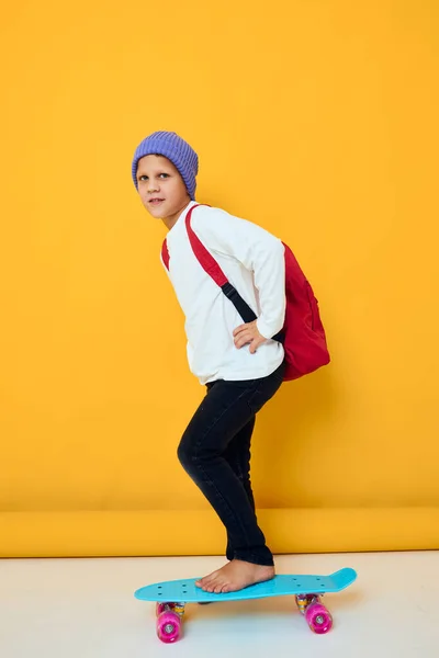 陽気な小さな子供は青い帽子でスケートボードに乗る子供時代のライフスタイルコンセプト — ストック写真