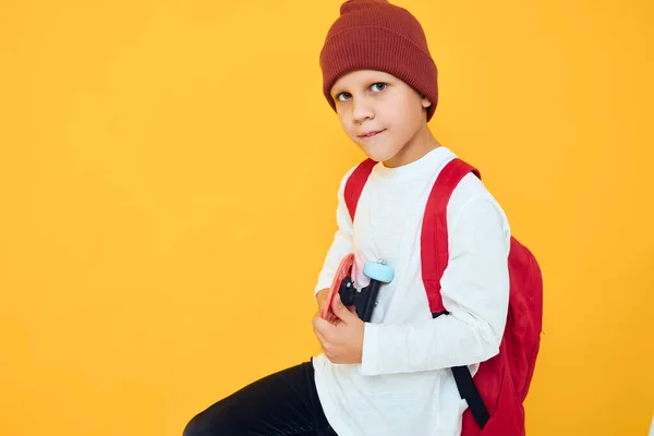 Porträtt av söta pojkar i en röd hatt skateboard i händerna isolerad bakgrund — Stockfoto
