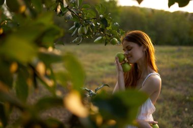 Elma ağacının yanında beyaz elbiseli bir kadın.