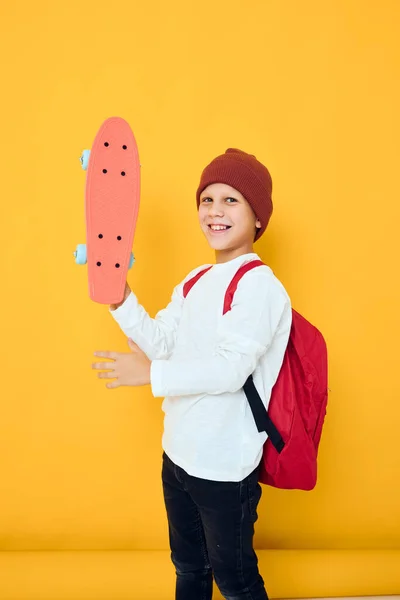 Retrato de meninos bonitos em um skate chapéu vermelho em suas mãos conceito de estilo de vida infantil — Fotografia de Stock