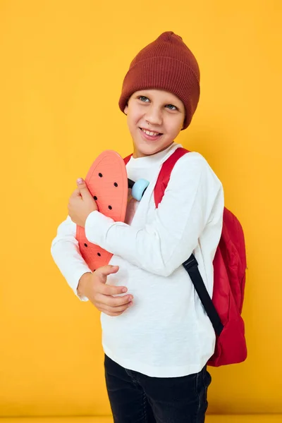 Cooler lächelnder Junge mit rotem Rucksack und rotem Skateboard — Stockfoto