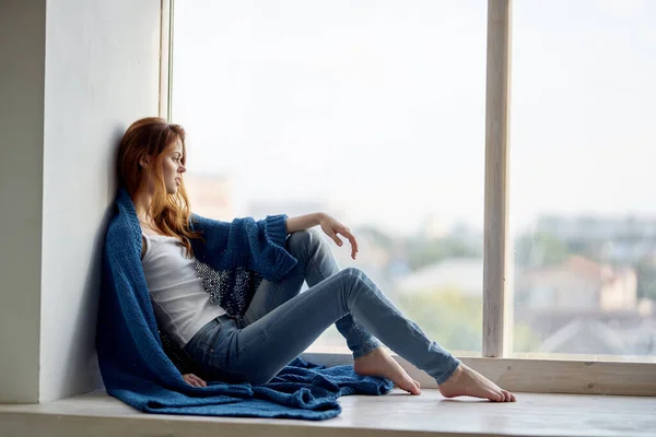 Piękna kobieta siedzi w pobliżu okna z niebieską kratę reszta — Zdjęcie stockowe