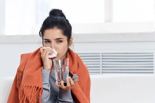 Nezle olmuş bir kadın, enfeksiyonu tedavi eden haplı bir bardak suyla kaplanmış. — Stok fotoğraf