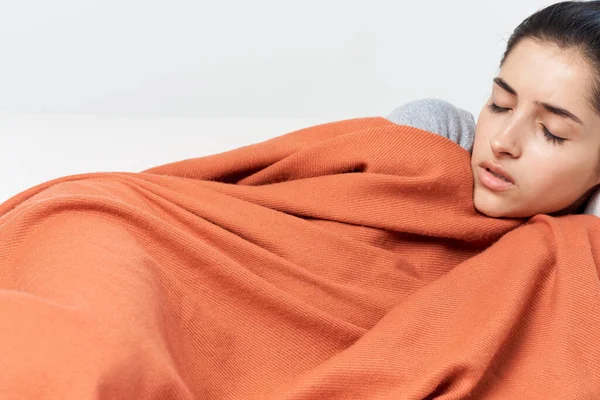 Жінка лежить вдома на дивані, покритому ковдрою із закритими очима холодно — стокове фото