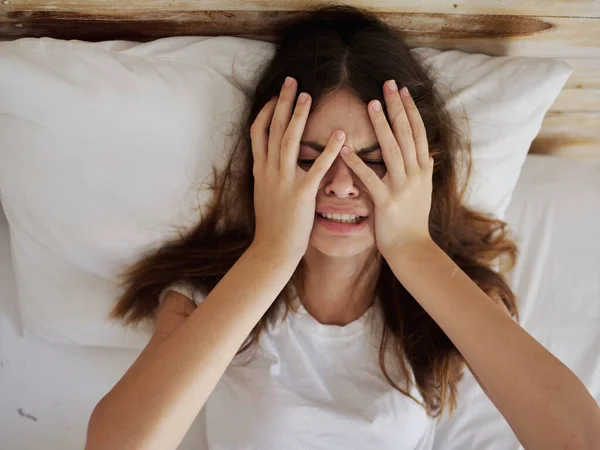 woman holding hands on face upset crying lying in bed