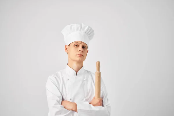 Um homem de uniforme de chefs segurando um rolo pin cozinhar comida restaurante cozinha — Fotografia de Stock