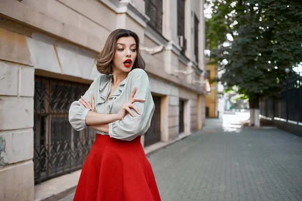 Симпатичная женщина в красной юбке по улице прогуливается возле здания — стоковое фото