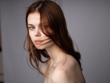 Kadın saçı, çıplak omuzlar, açık ten rengi, koyu renk arka plan.