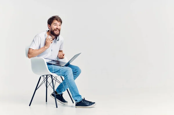 bearded man sitting on a chair with a laptop in headphones Lifestyle