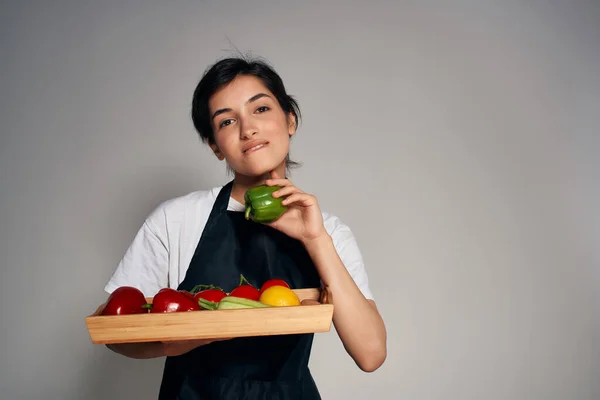 Mujer alegre en un delantal negro verduras tareas domésticas cocina — Foto de Stock