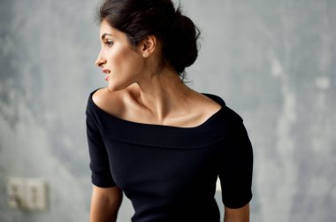 Siyah elbiseli çekici kadın yakın plan poz veriyor.