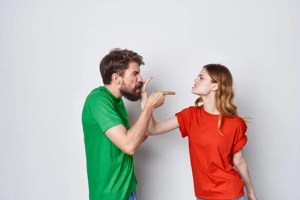 Een jong stel veelkleurige t-shirts communicatie ruzie lichte achtergrond — Stockfoto