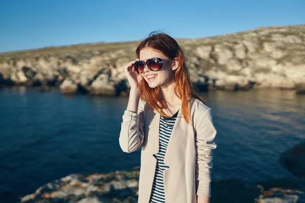 Mujer usando gafas de sol rocas paisaje mar — Foto de Stock