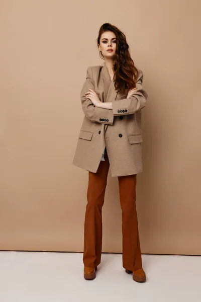 Hermosa mujer en pantalones marrones abrigo beige y botas con tacones —  Fotos de Stock