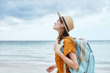 Kumsalda sırt çantalı kadın turist temiz hava alıyor.