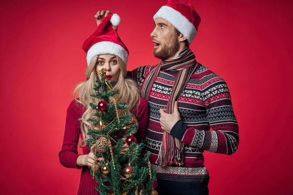 Mann und Frau Weihnachtsbaum Spielzeug Spaß Urlaub rot Hintergrund — Stockfoto