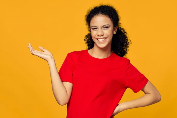 Mulher alegre em gestos t-shirt vermelho com a mão Copiar Espaço fundo amarelo — Fotografia de Stock