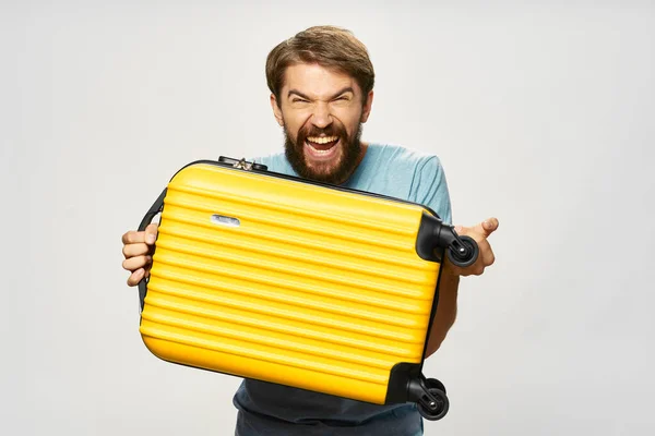 Hombre agresivo con maleta amarilla camisa azul modelo fondo claro — Foto de Stock