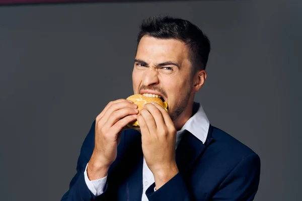 O homem na tela Burger comida lanche o fundo escuro — Fotografia de Stock