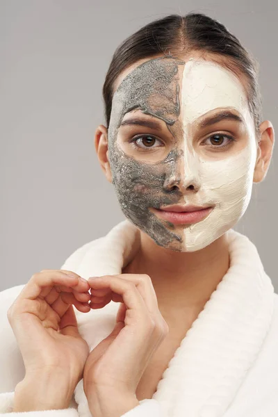 Mujer en un albornoz con una máscara en su cara cuidado de la piel rejuvenecimiento —  Fotos de Stock