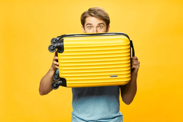 Hombre sosteniendo maleta pasajero viaje aeropuerto amarillo fondo —  Fotos de Stock