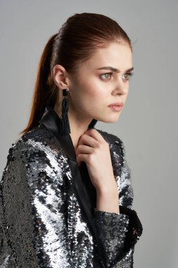 Gümüş ceketli çekici bir kadın. Göz alıcı bir yan bakış.